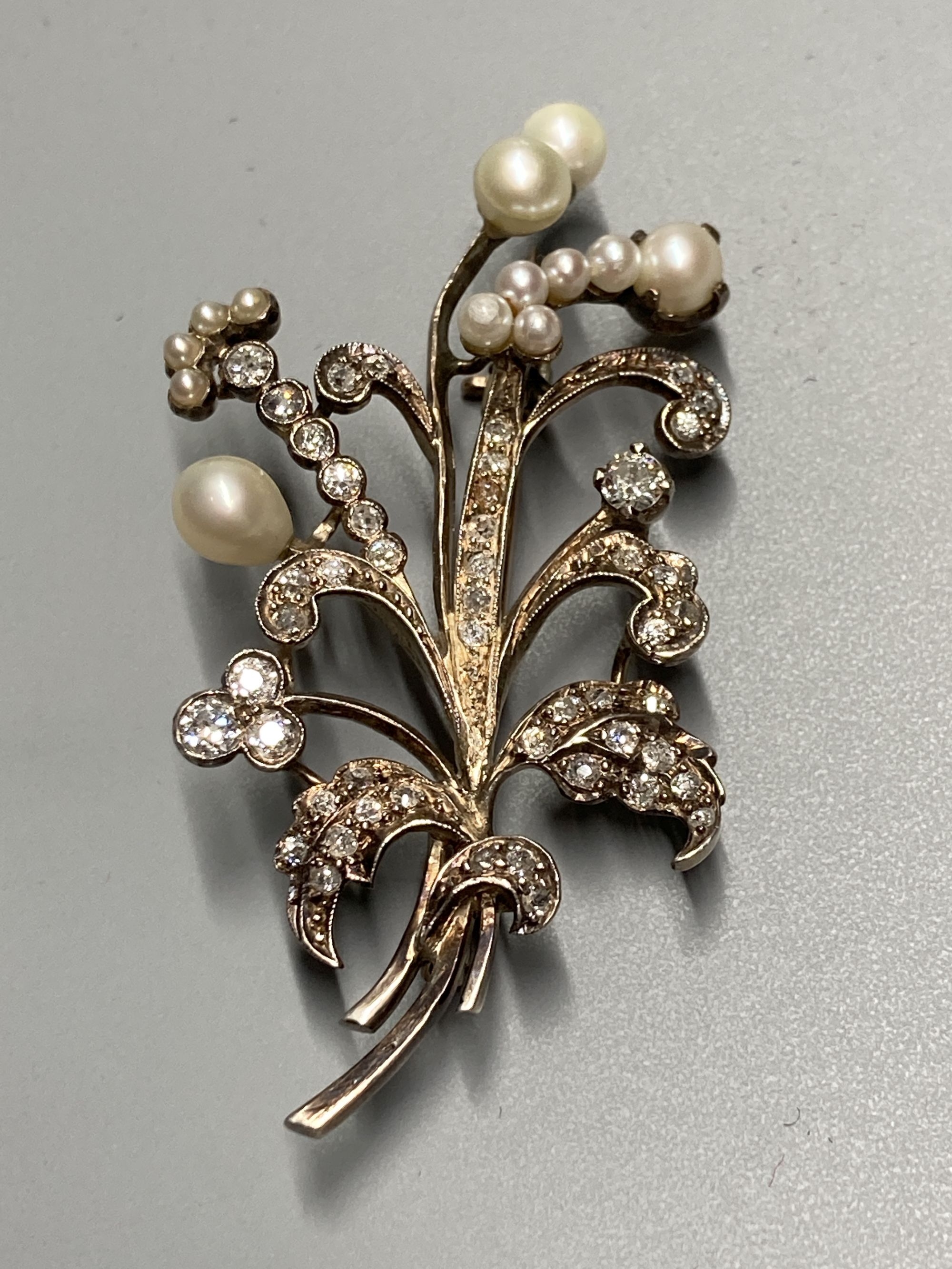 An early 20th century yellow and white metal, cultured pearl and diamond set floral spray brooch, 6cm, gross 12.6 grams.